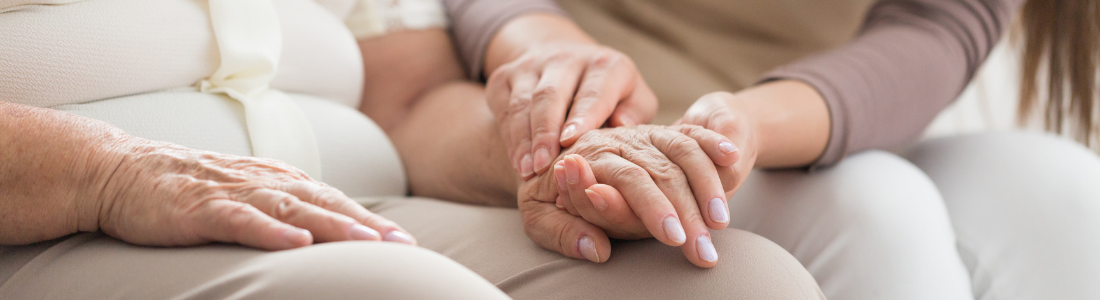 Carer holding the hand of an elderly person