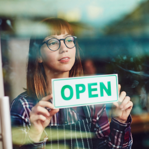 Woman with open sign after taking her first commercial lease