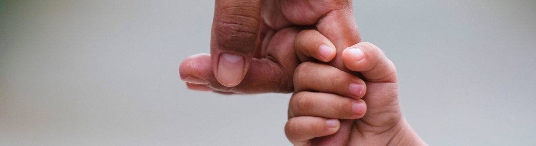 Child's small hand holding a parent's finger during internal relocation